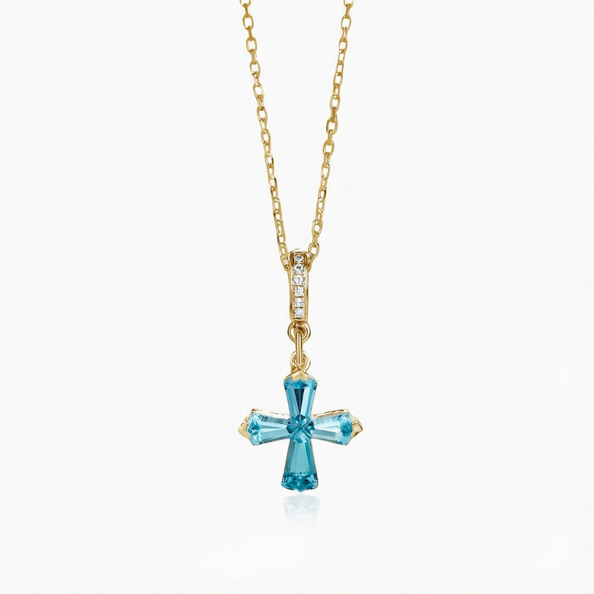 Gold necklace with a blue gemstone cross pendant on a white background | SARATTI - Natural Aquamarine Necklace in 18K Yellow Gold