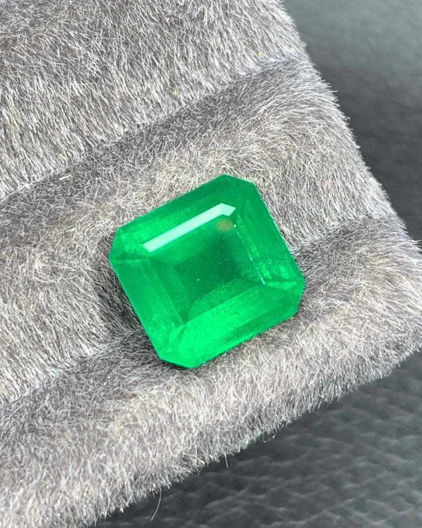 Close-up of a 4.95 CTS Vivid Green Natural Emerald showing broad step-cut facets and geometric light reflections | SARATTI