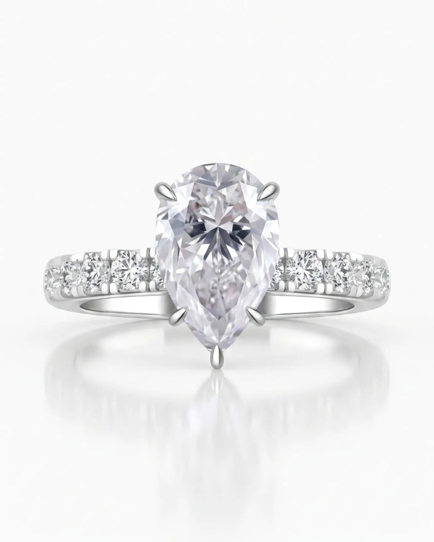 Colorless pear-shaped moissanite center with round accent stones and hidden halo in platinum | SARATTI