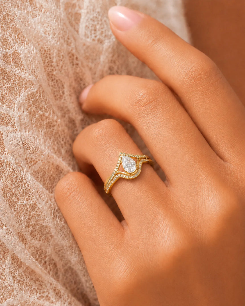 Colorless pear moissanite center surrounded by brilliant round stones in polished 18K yellow gold | SARATTI