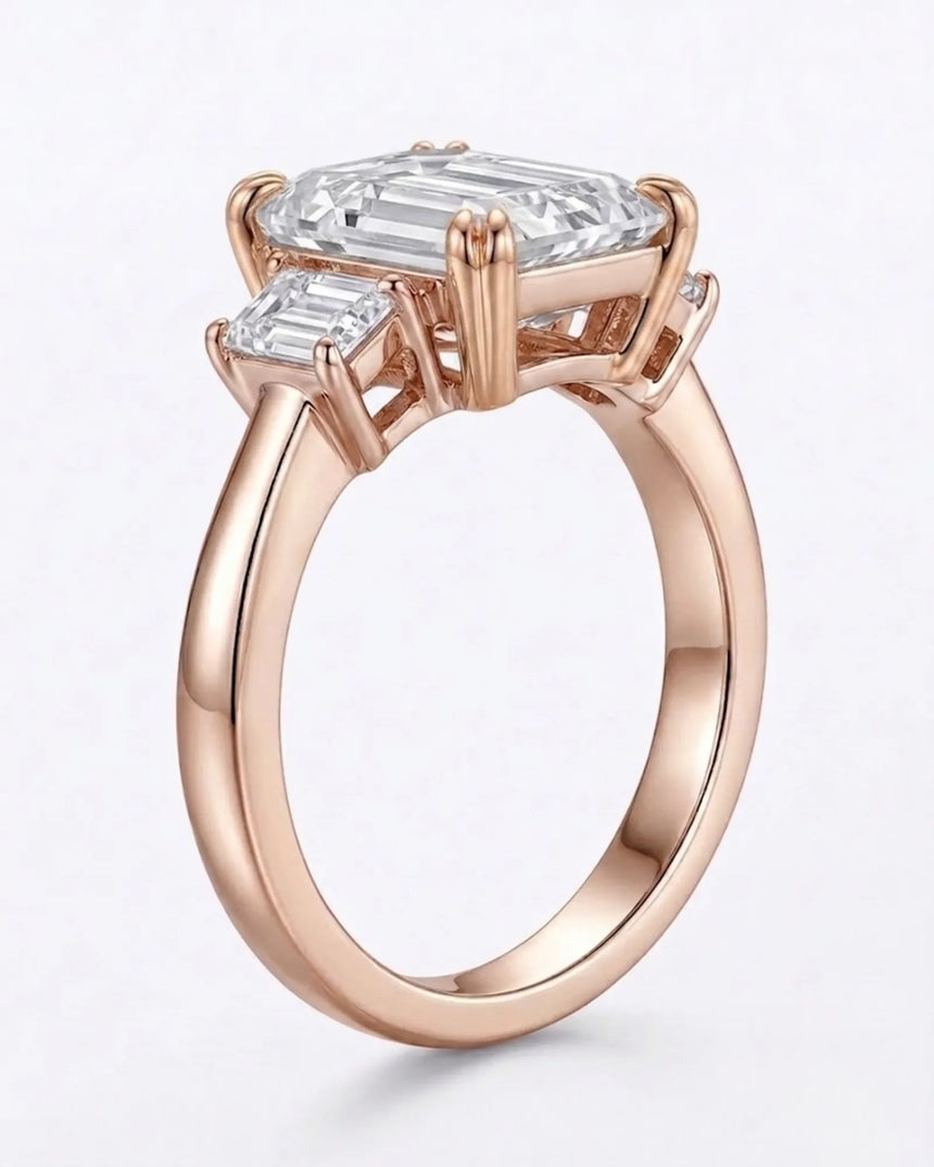 D color emerald cut moissanite center with matching side stones in warm 18K rose gold | SARATTI
