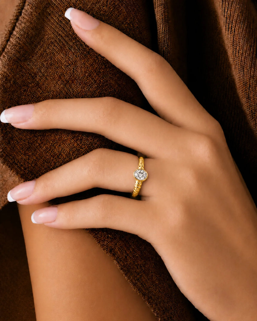 D color oval moissanite framed by a smooth bezel in warm 18K yellow gold | SARATTI