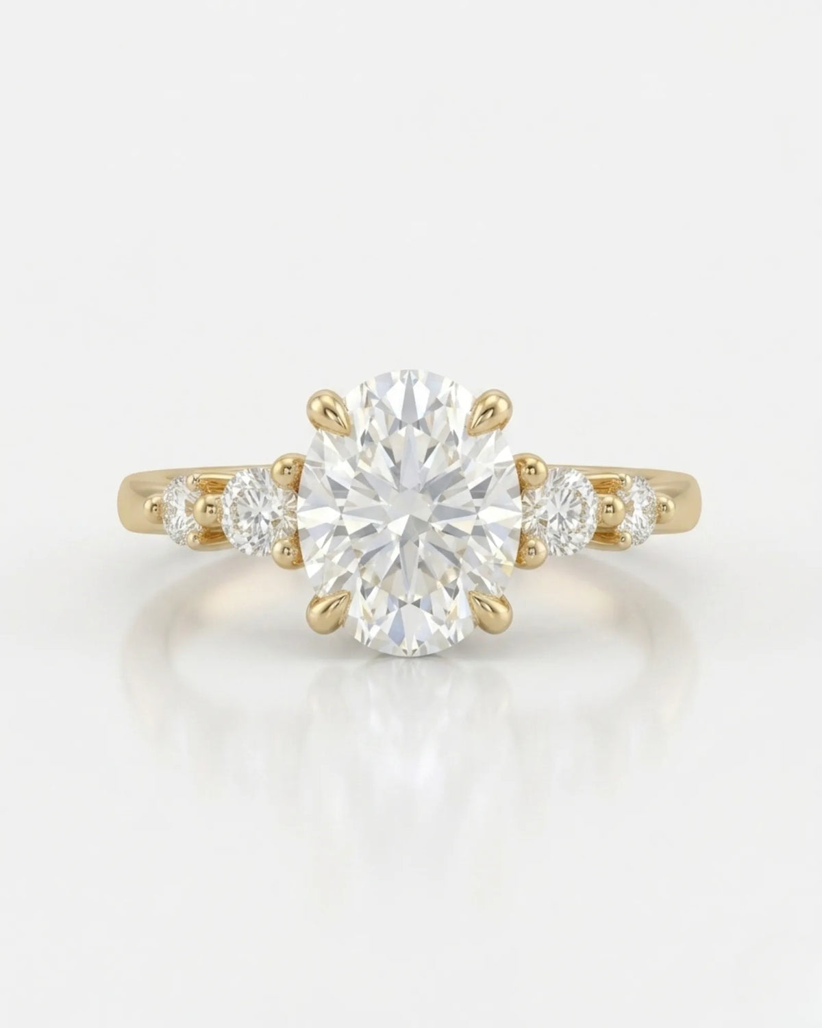 D color oval moissanite framed by round side stones in polished 18K yellow gold | SARATTI