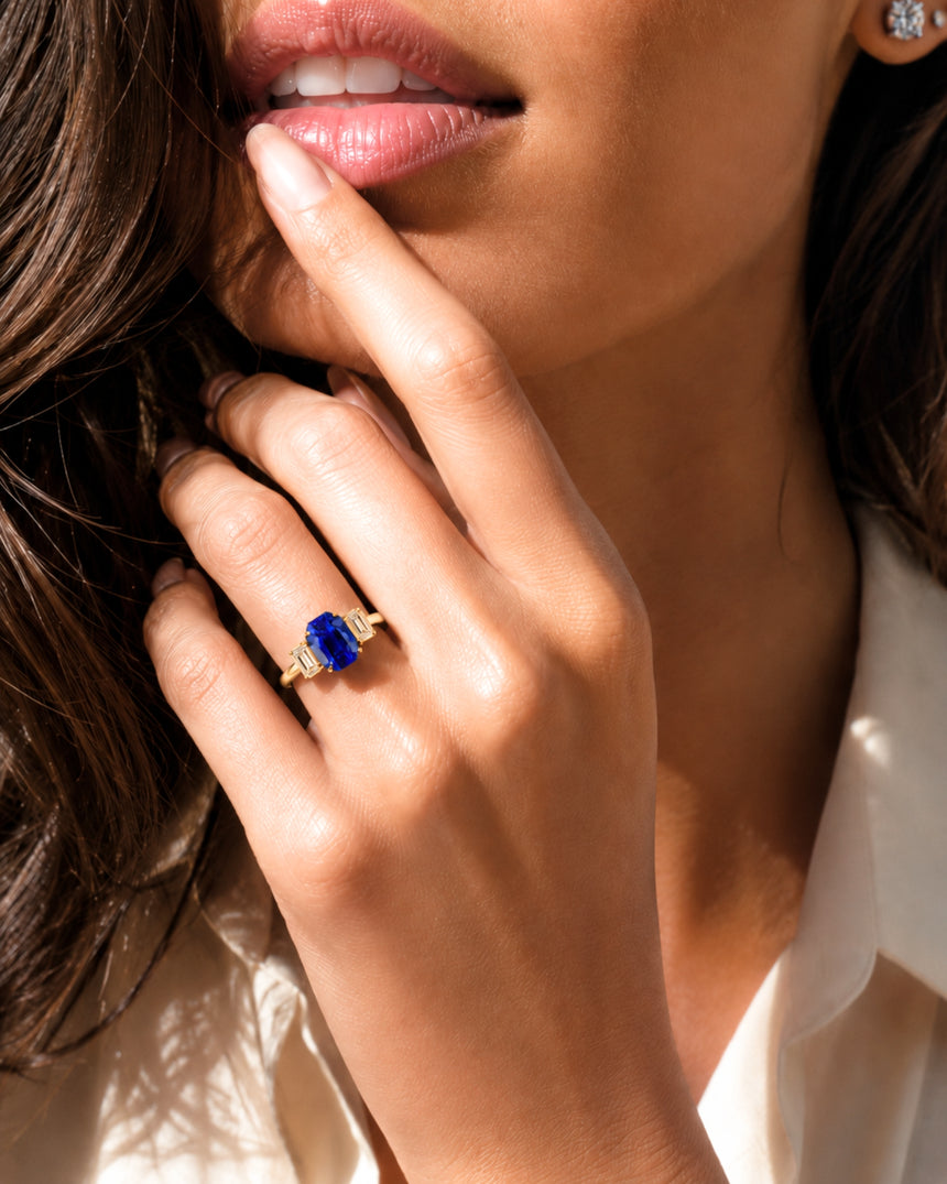 Natural emerald cut blue sapphire ring with matching diamond side stones in 18K yellow gold | SARATTI