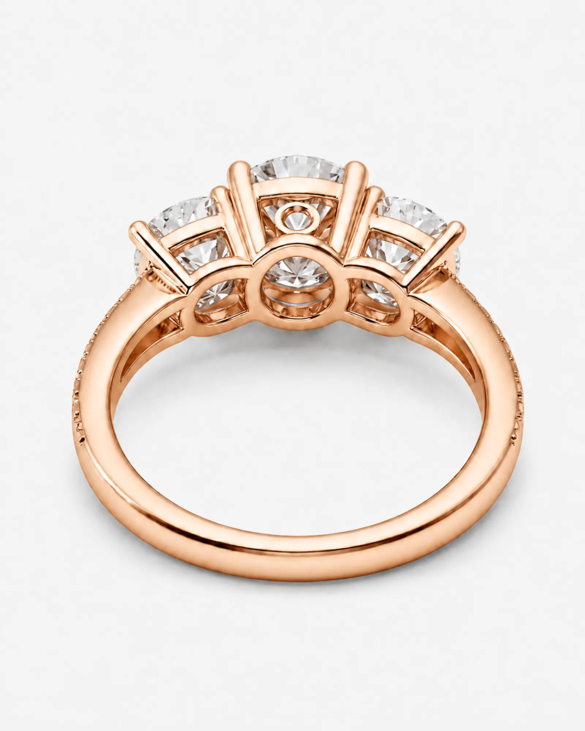 Round moissanite trilogy design framed by graduated side stones in warm 18K rose gold | SARATTI.