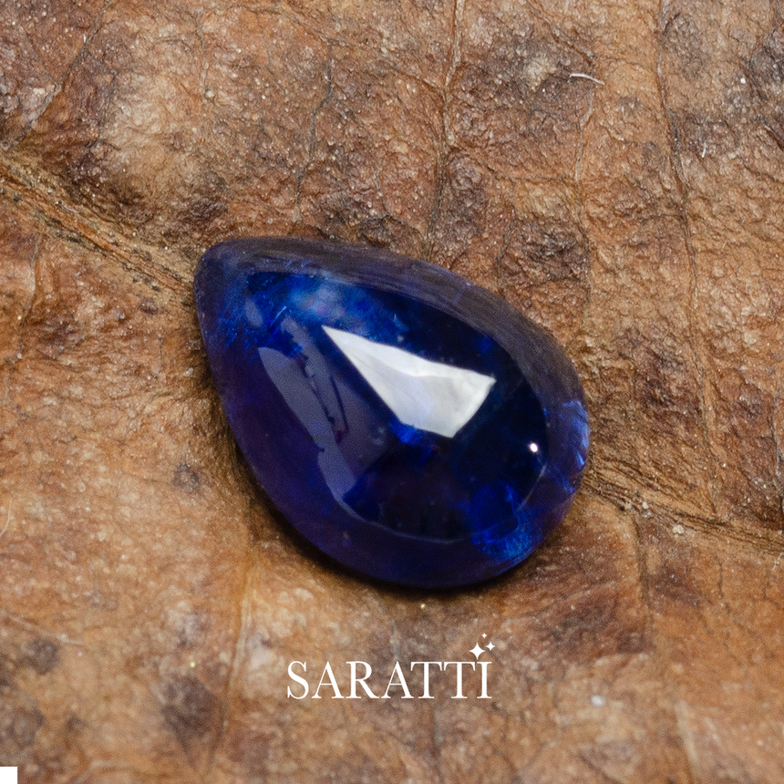Pear cabochon blue sapphire gemstone close-up on natural surface | SARATTI