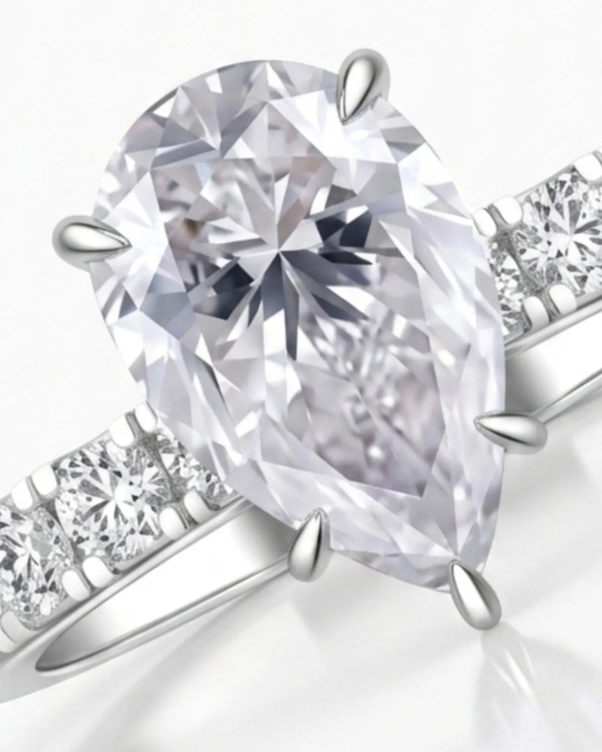 Sculptural pear moissanite ring with hidden halo and accented shoulders in polished 18K white gold - SARATTI