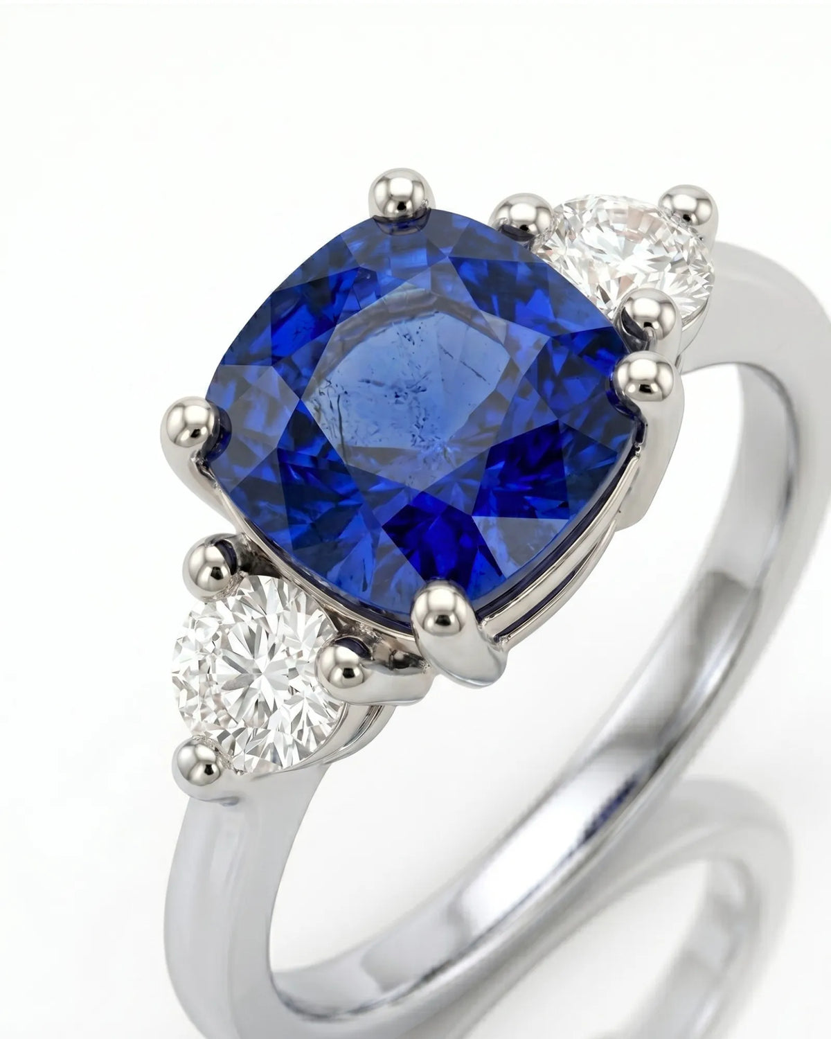 Three stone sapphire ring with round diamond accents in polished platinum | SARATTI
