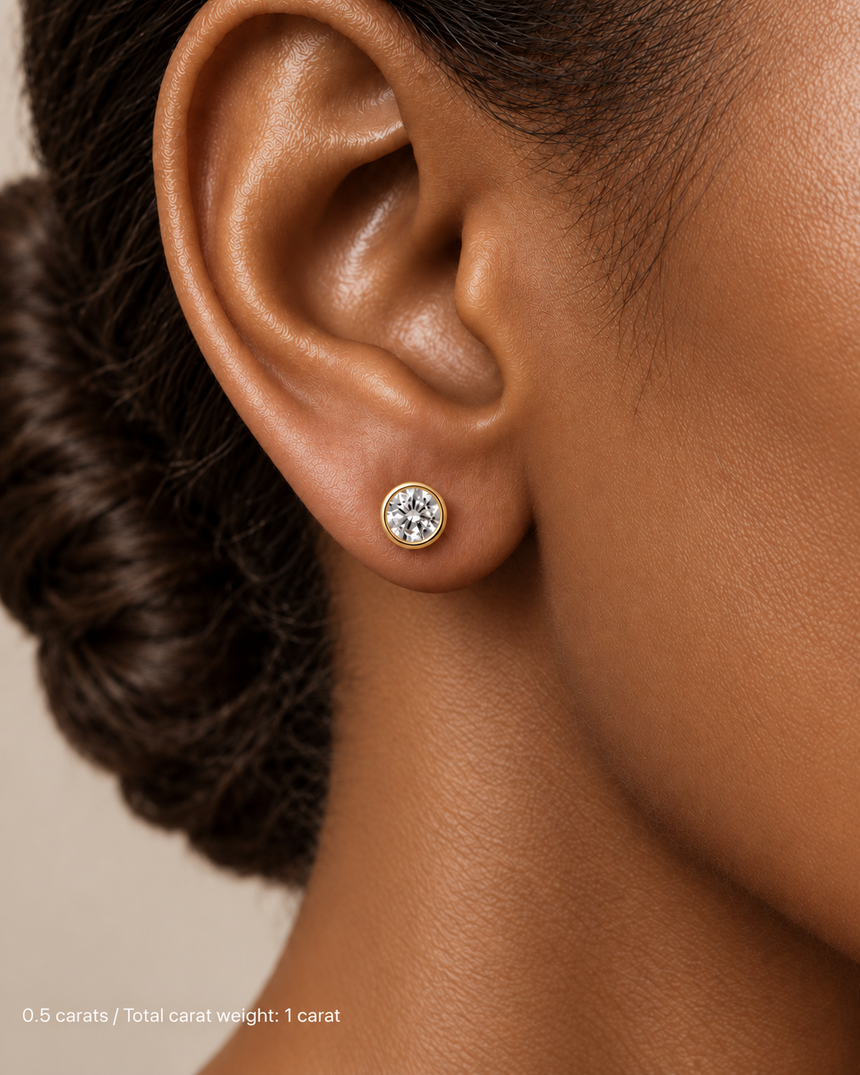 1.00 ct. tw. lab-grown round diamond full-bezel studs in 14K yellow gold on deep skin | SARATTI