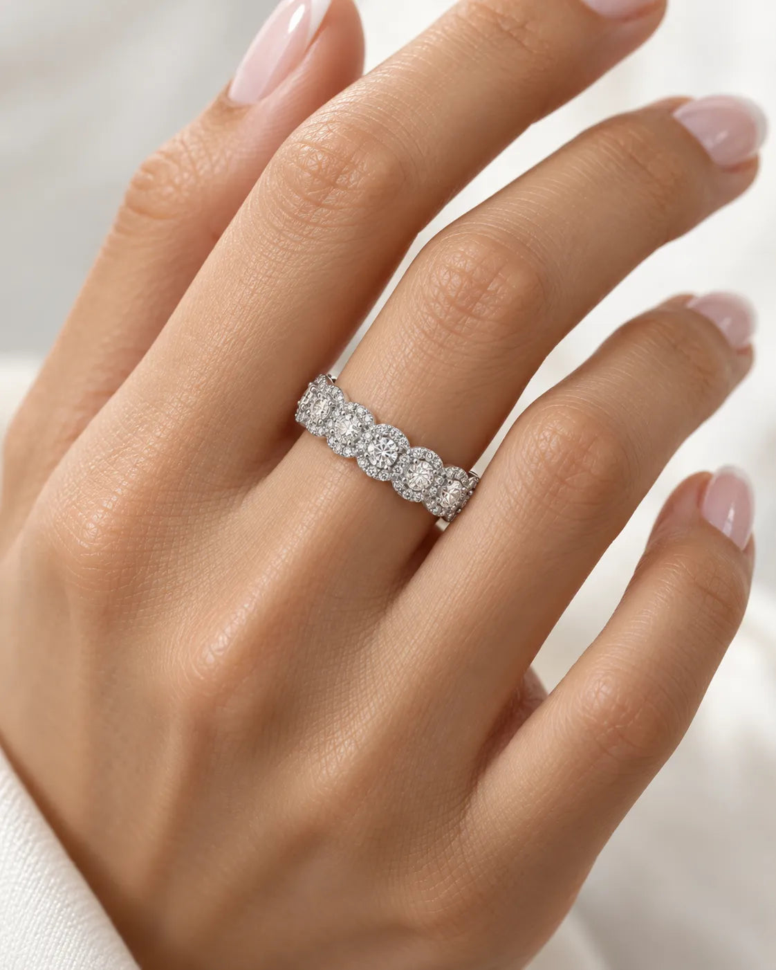 Round diamond cluster eternity band in platinum shown on the hand | SARATTI