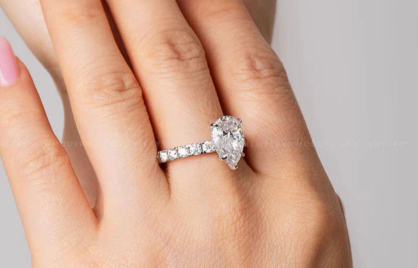 Pear Cut Diamond Engagement Ring with Diamond Accents on Model's Finger | Saratti 