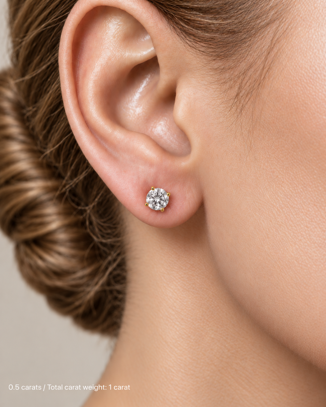 1.00 ct. tw. lab-grown round diamond studs in 14K yellow gold, fair skin on-ear model | SARATTI