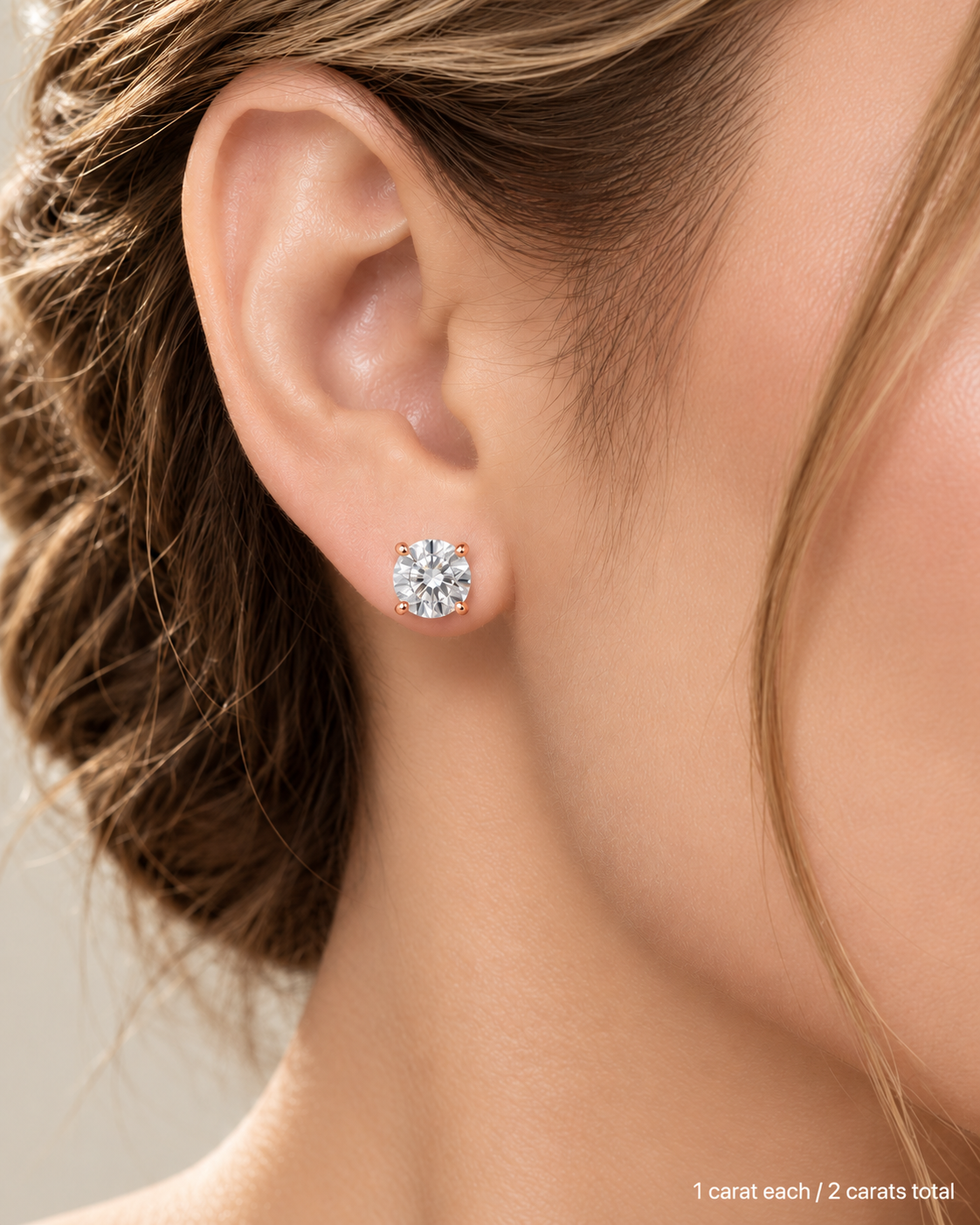 2.00 ct. tw. lab-grown round diamond studs in 18K rose gold, fair skin on-ear model | SARATTI