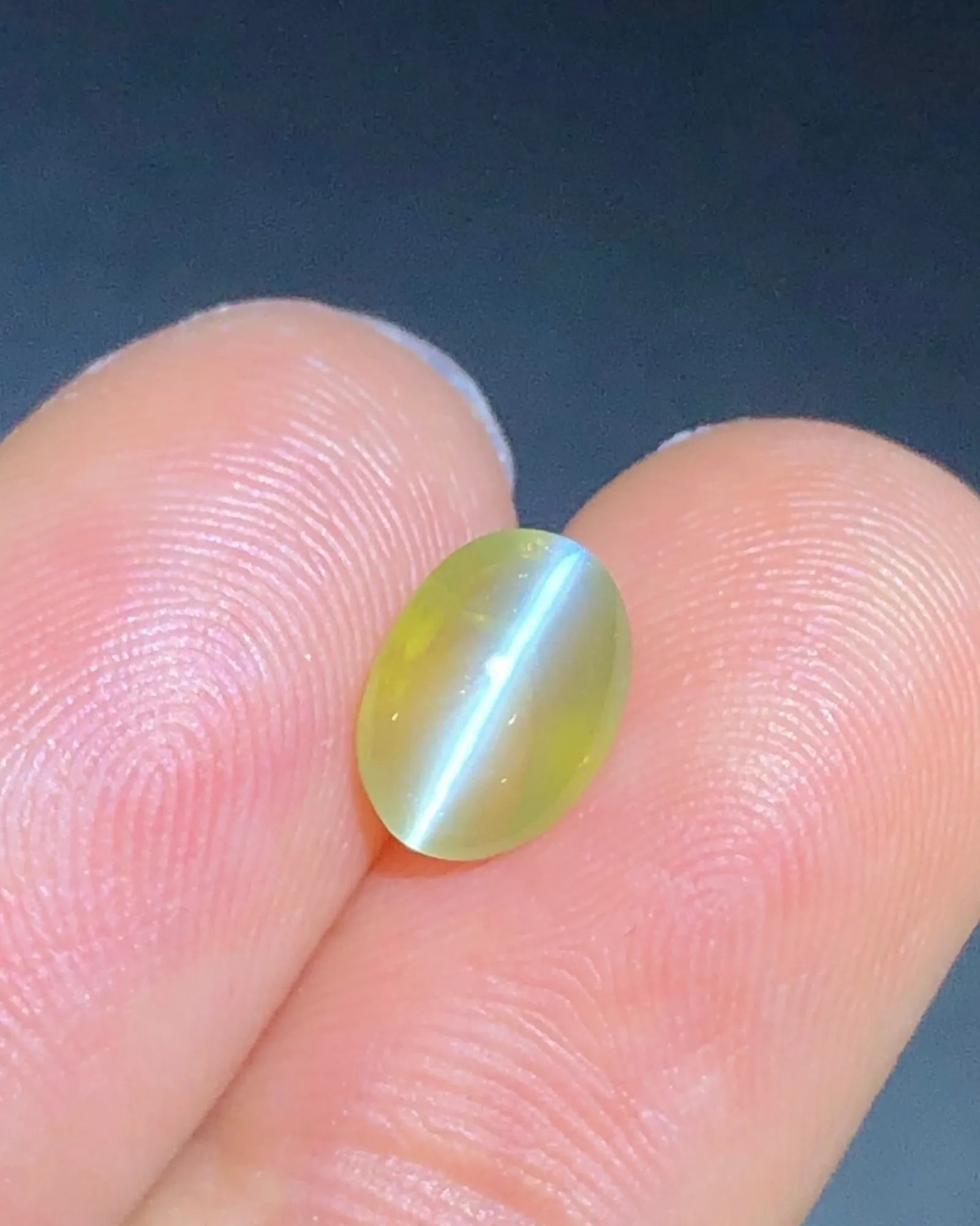 Close-up of 2.23 carat Yellowish Green Cat's-Eye Chrysoberyl showing a concentrated chatoyant band across the oval cabochon