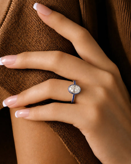 Bezel-set oval natural diamond ring with blue sapphire halo and pavé band in 18K white gold | SARATTI