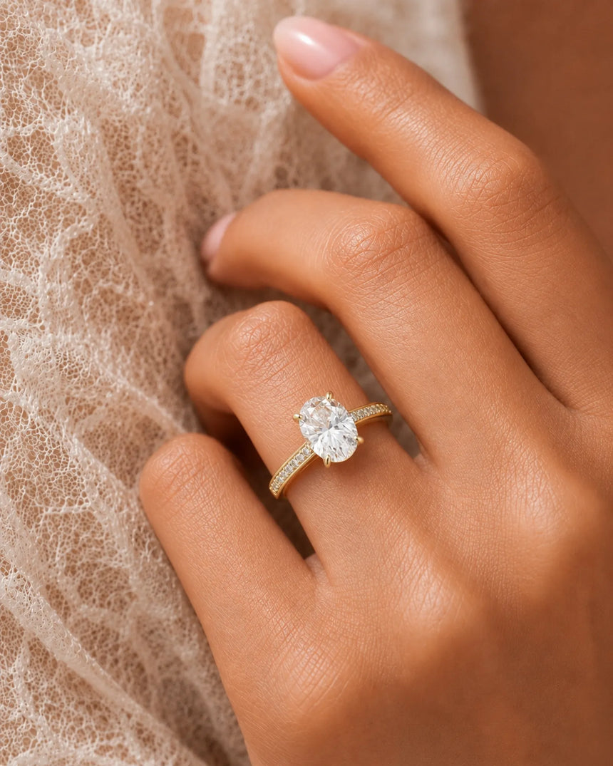 Classic oval moissanite ring with four prong setting and pavé band in yellow gold | SARATTI