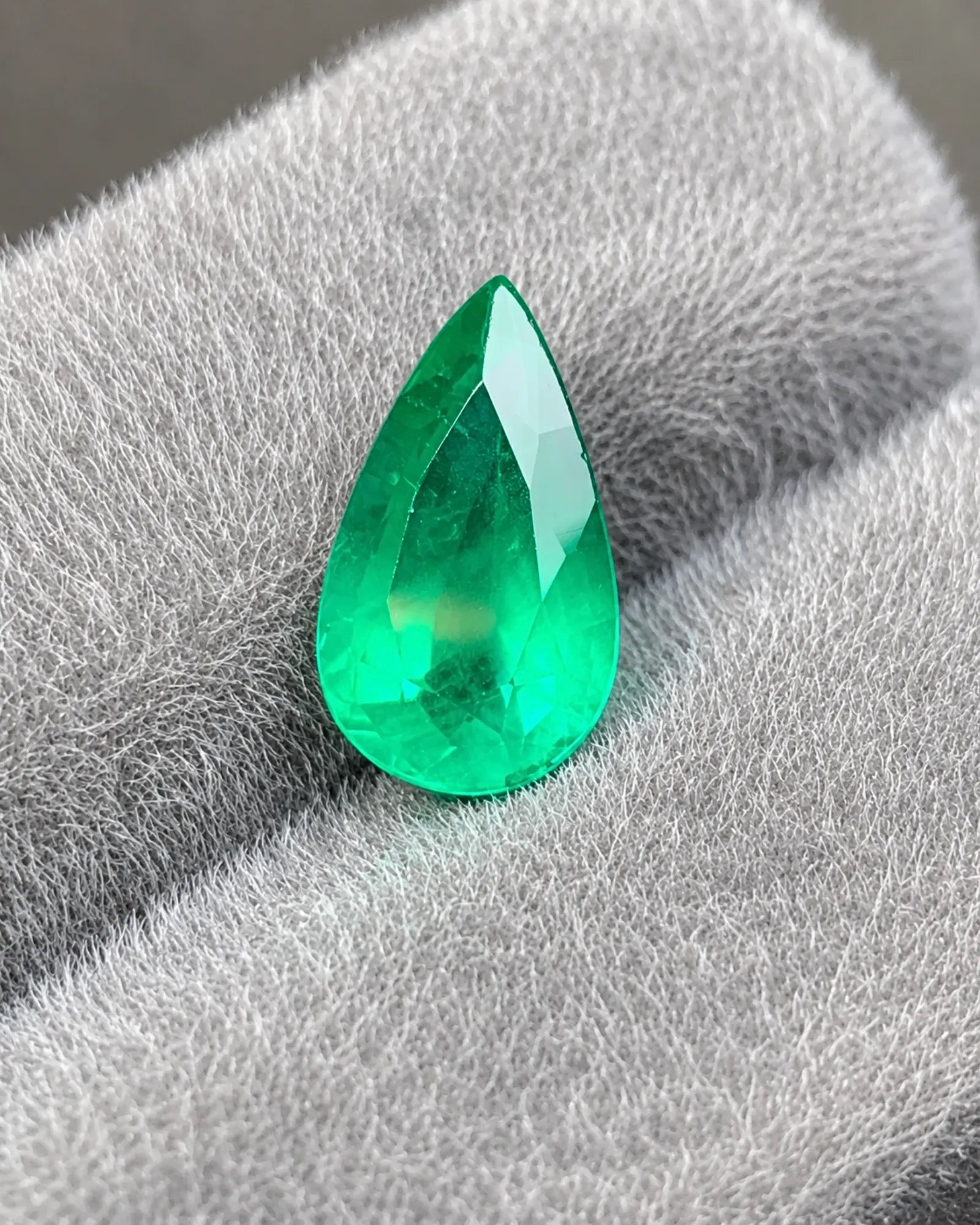 Close-up of modified brilliant facets on a vivid green pear Emerald | SARATTI