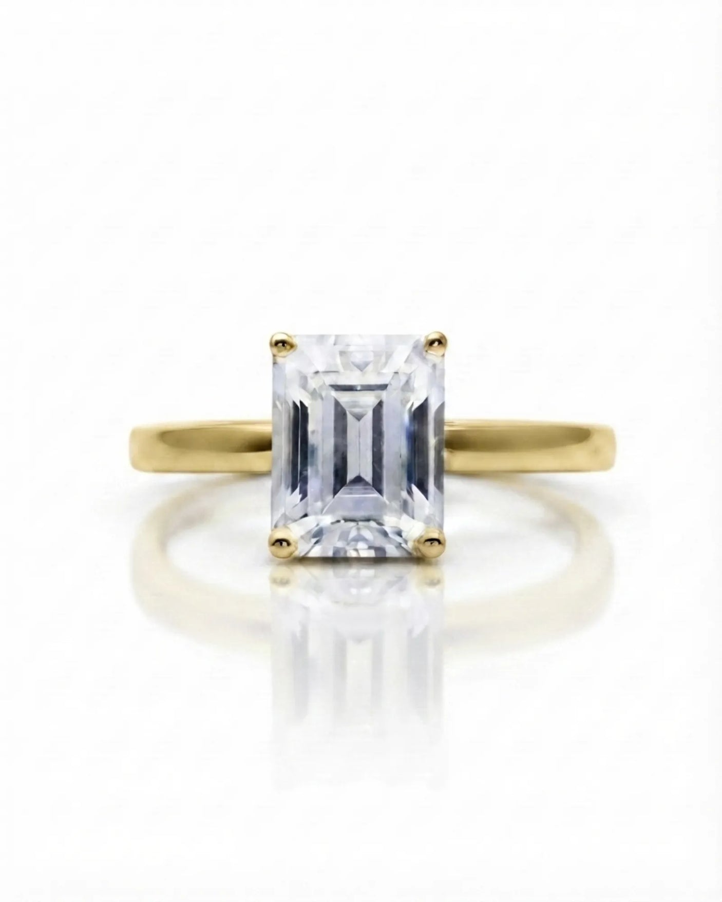Colorless emerald-cut moissanite ring with step-cut facets and warm yellow gold setting | SARATTI