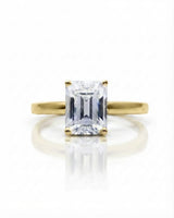 Colorless emerald-cut moissanite ring with step-cut facets and warm yellow gold setting | SARATTI