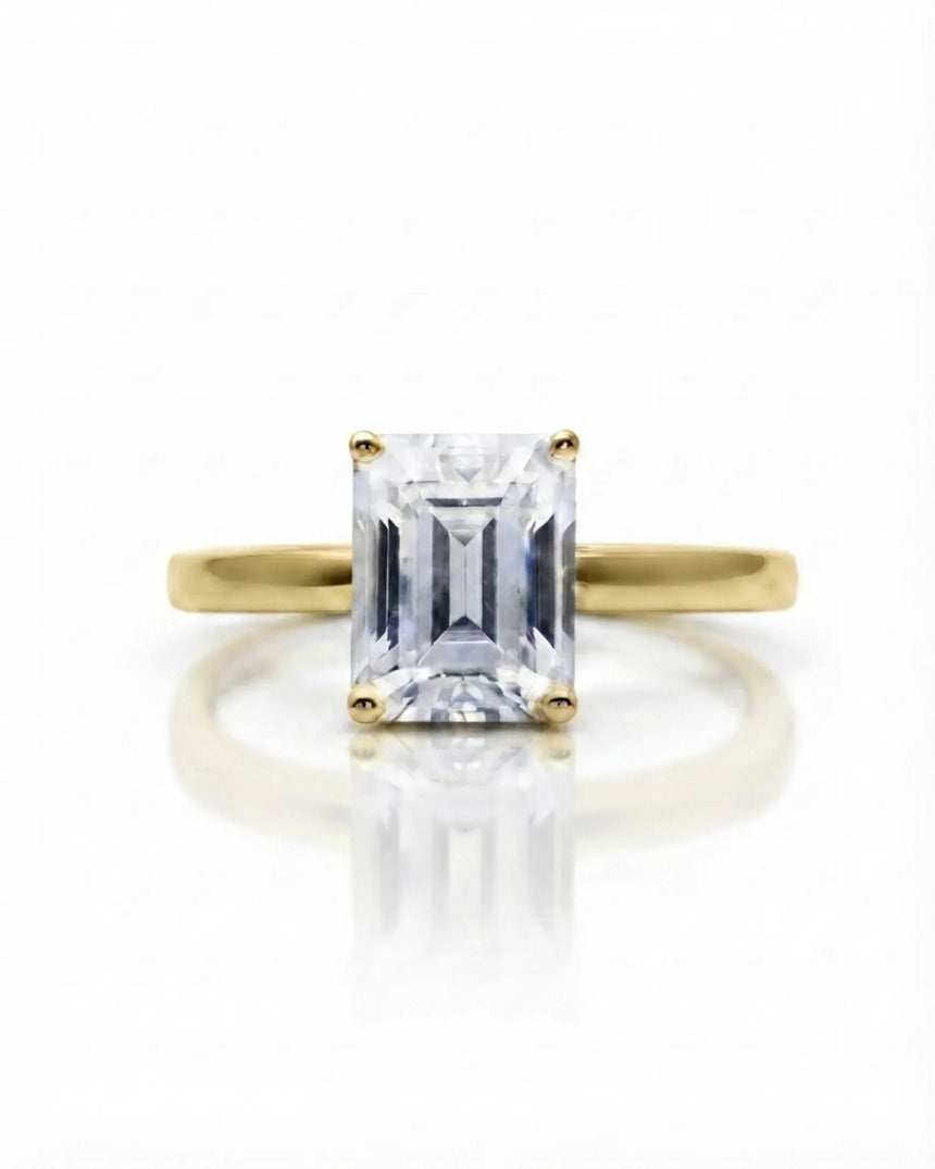Colorless emerald-cut moissanite ring with step-cut facets and warm yellow gold setting | SARATTI