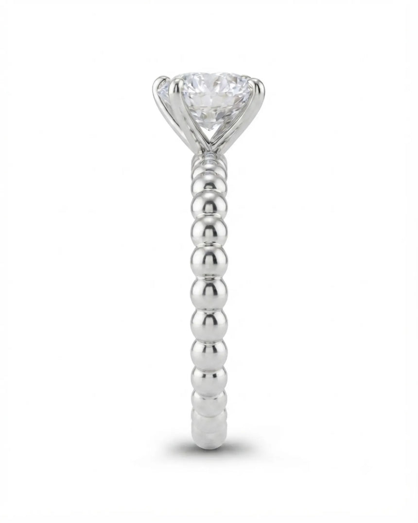 Colorless round moissanite ring framed by four platinum prongs and rhythmic spherical detailing | SARATTI