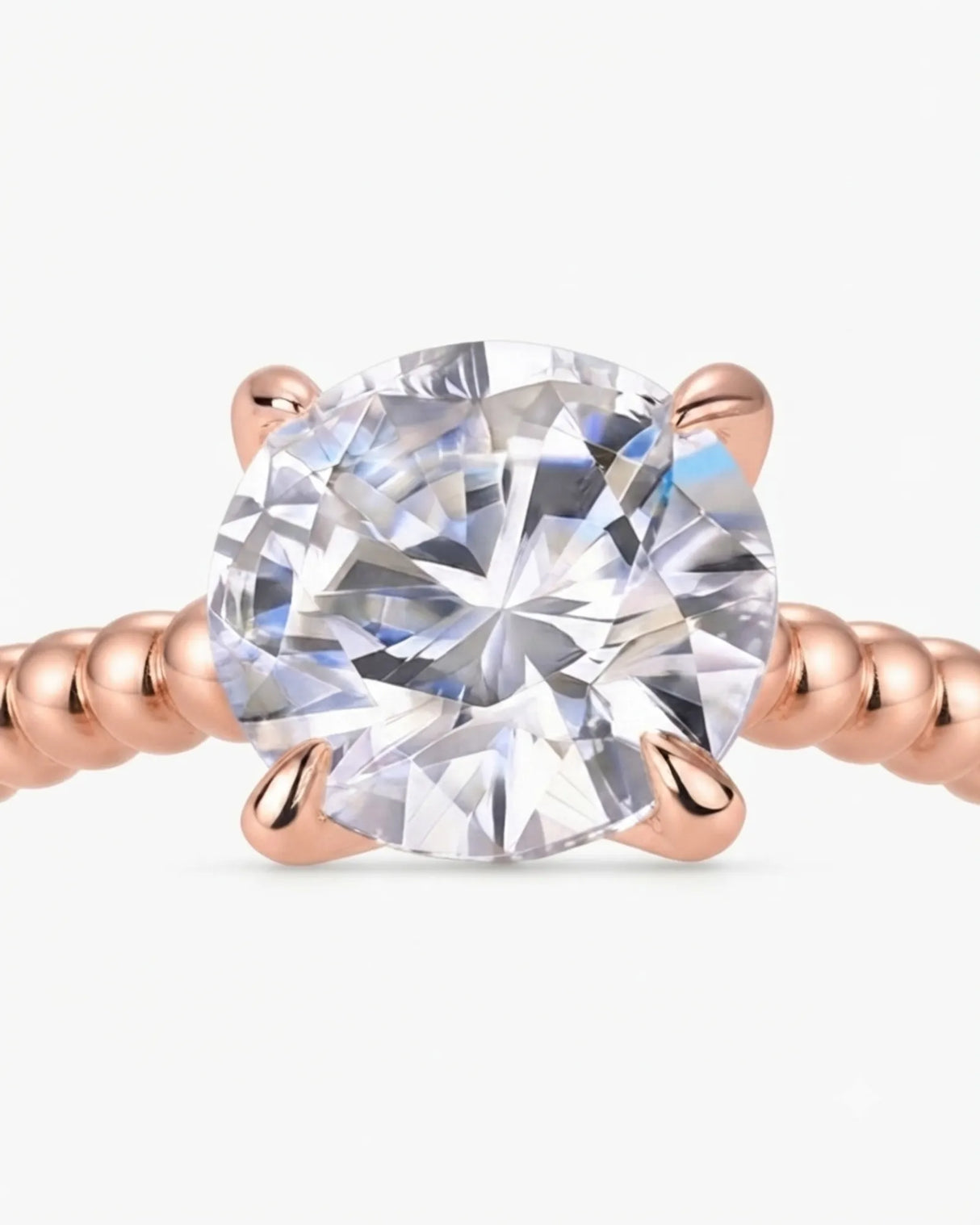 Colorless round moissanite ring framed by four rose gold prongs and rhythmic spherical detailing | SARATTI