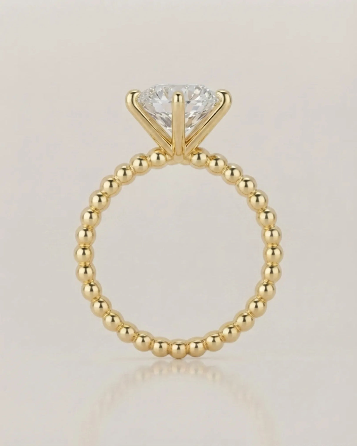 Colorless round moissanite ring framed by four yellow gold prongs and rhythmic spherical detailing | SARATTI