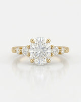D color oval moissanite framed by round side stones in polished 18K yellow gold | SARATTI