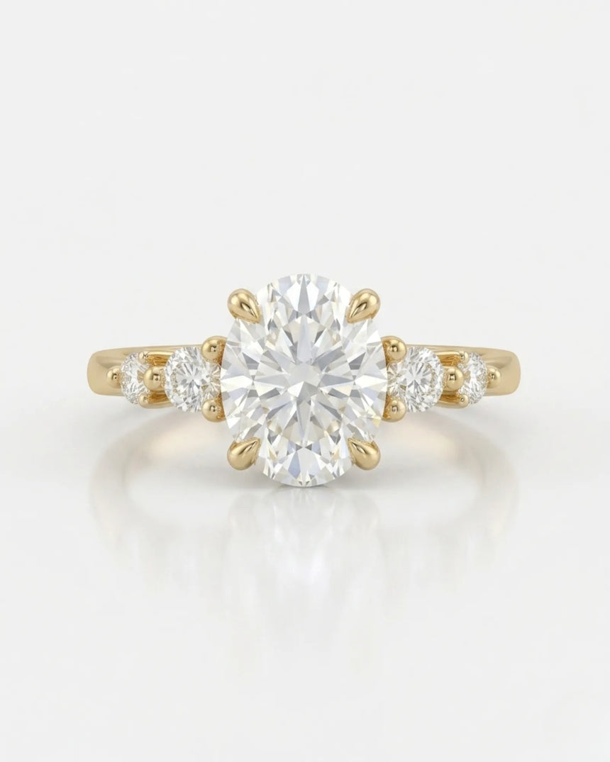 D color oval moissanite framed by round side stones in polished 18K yellow gold | SARATTI