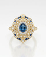 Deep London Blue oval topaz ring framed by round diamonds in 18K yellow gold | SARATTI