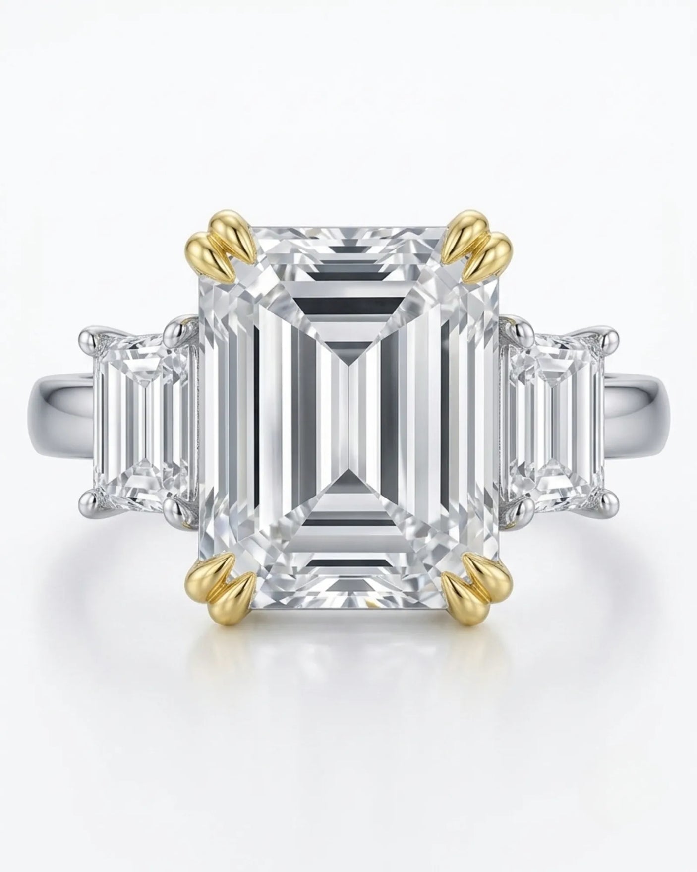 Emerald-cut center diamond framed by step-cut side diamonds in a refined two tone gold setting | SARATTI