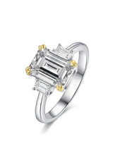 Emerald cut moissanite three stone engagement ring with yellow claw prongs in two tone | SARATTI