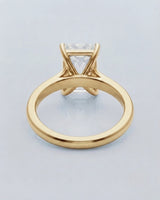 Emerald moissanite solitaire ring in yellow gold with architectural basket and clean minimalist profile | SARATTI