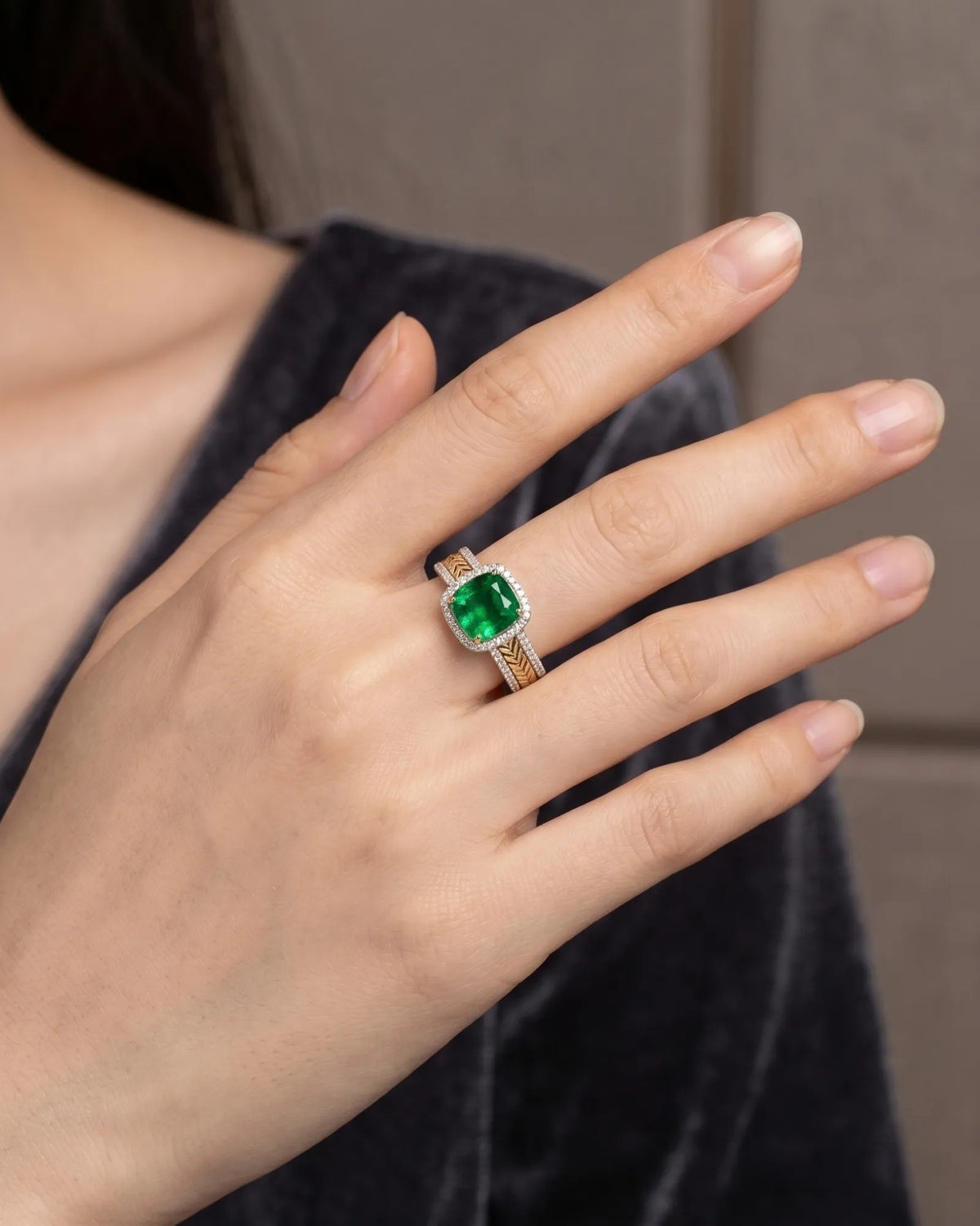 Emerald woven ring featuring a diamond halo and textured interlocking 18K two tone gold shoulders | SARATTI