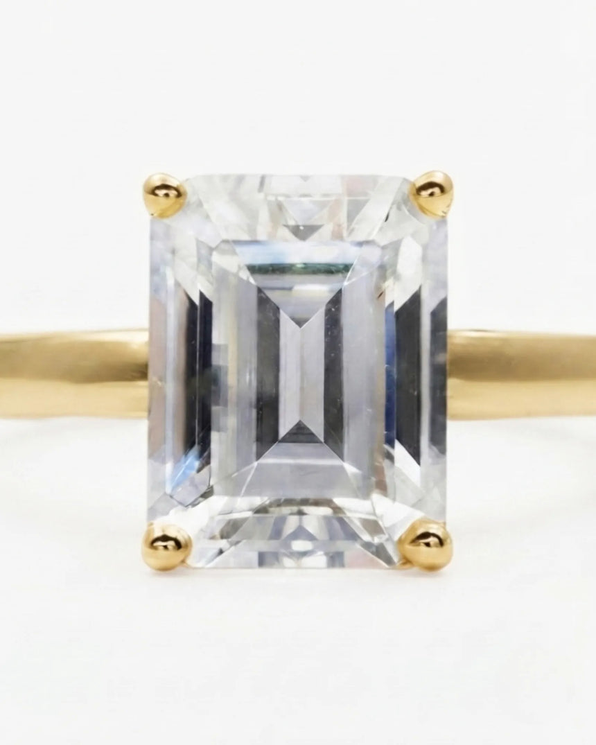 Luxury emerald-cut moissanite solitaire ring with polished yellow gold band and open gallery | SARATTI