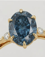 Luxury oval blue moissanite ring with accent stones and rich yellow gold finish | SARATTI