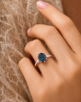 Luxury oval blue moissanite ring with accent stones and warm rose gold finish | SARATTI