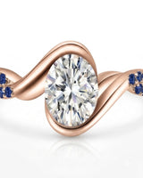 Luxury oval moissanite and natural sapphire ring with sculptural rose gold ribbon setting | SARATTI.