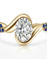 Luxury oval moissanite and natural sapphire ring with sculptural yellow gold ribbon setting | SARATTI.