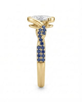 Luxury oval moissanite and natural sapphire ring with sculptural yellow gold ribbon setting | SARATTI