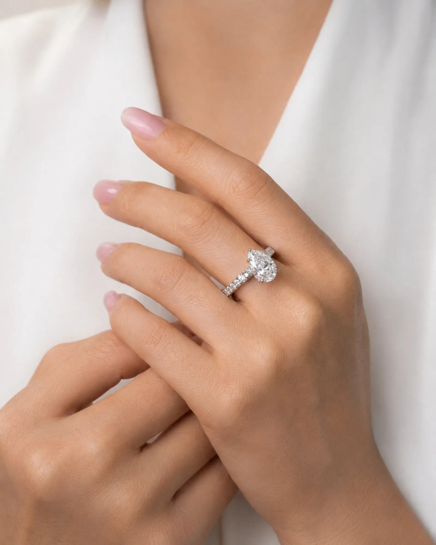 Luxury pear cut moissanite ring with sculptural gallery and brilliant shoulder accents in 18K white gold | SARATTI