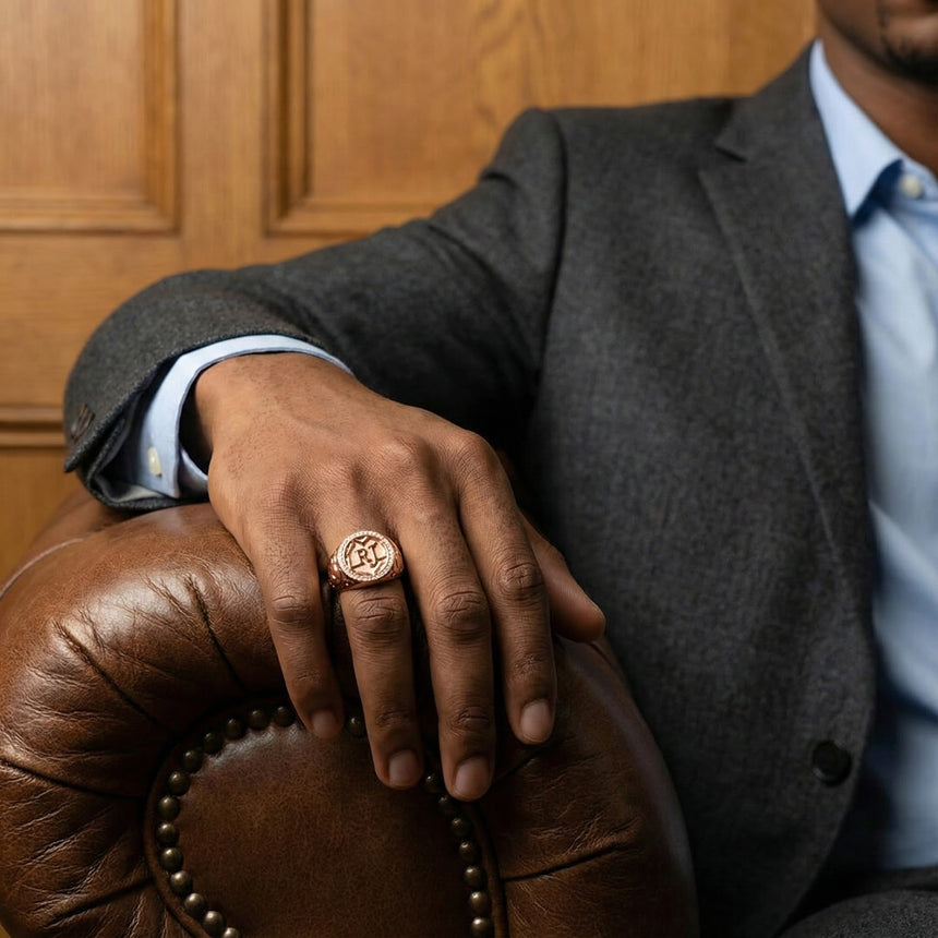 Man in a suit with a ring on his hand, sitting on a leather chair. | Men Vintage Signet Diamond Ring in 18K Rose Gold - SARATTI