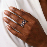 Hand wearing a ring with blue stones and clear stones on a white background - Multi row sapphire diamond ring rose gold finish | SARATTI