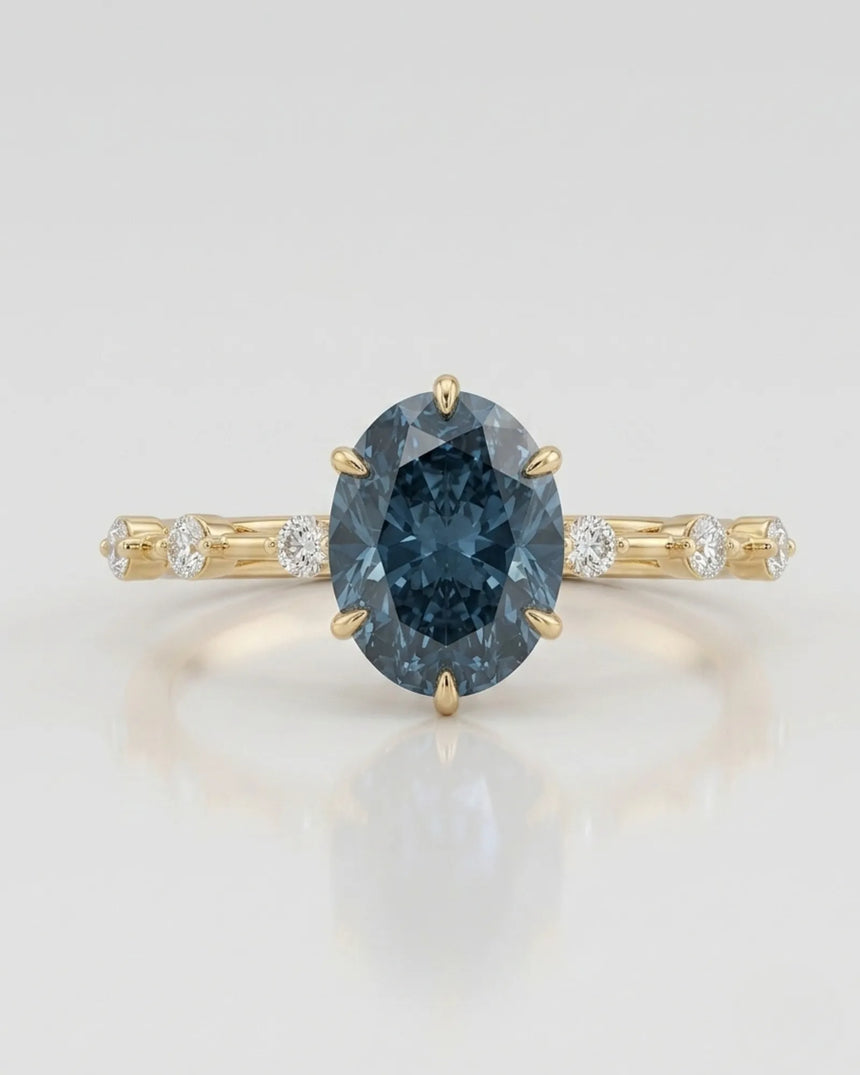 Oval blue moissanite center with colorless round side stones in 18K yellow gold | SARATTI