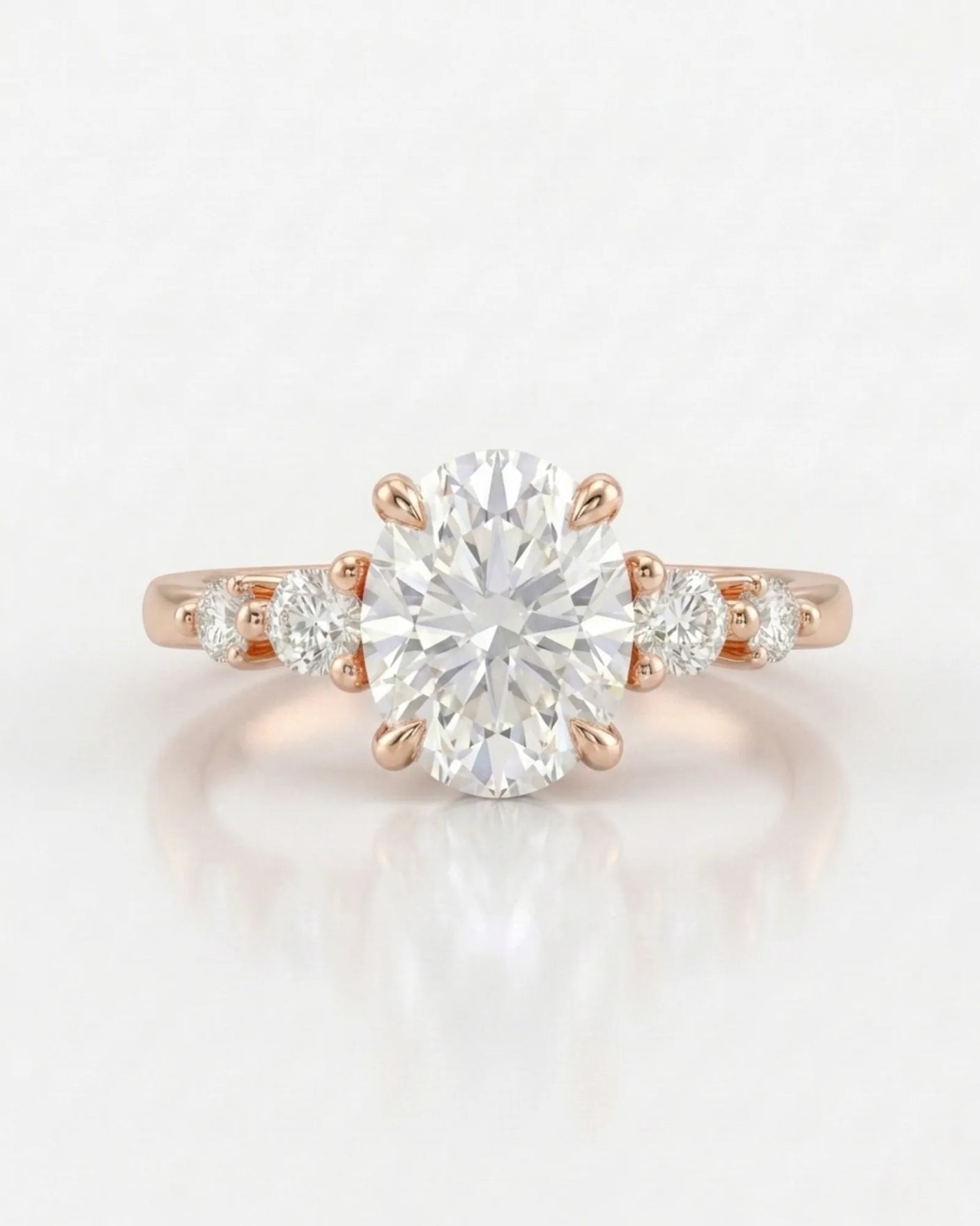 Oval centre diamond framed by softly spaced round diamonds in a warm 18K rose gold setting | SARATTI