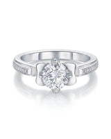 Profile view of round moissanite ring with pavé stones and sculpted fleur-de-lis gallery in 18K white gold | SARATTI