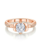 Round moissanite proposal ring with pavé side stones and symbolic fleur-de-lis setting in 18K rose gold | SARATTI