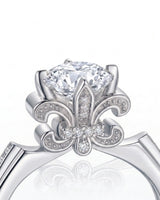 Round moissanite proposal ring with pavé side stones and symbolic fleur-de-lis setting in 18K white gold | SARATTI