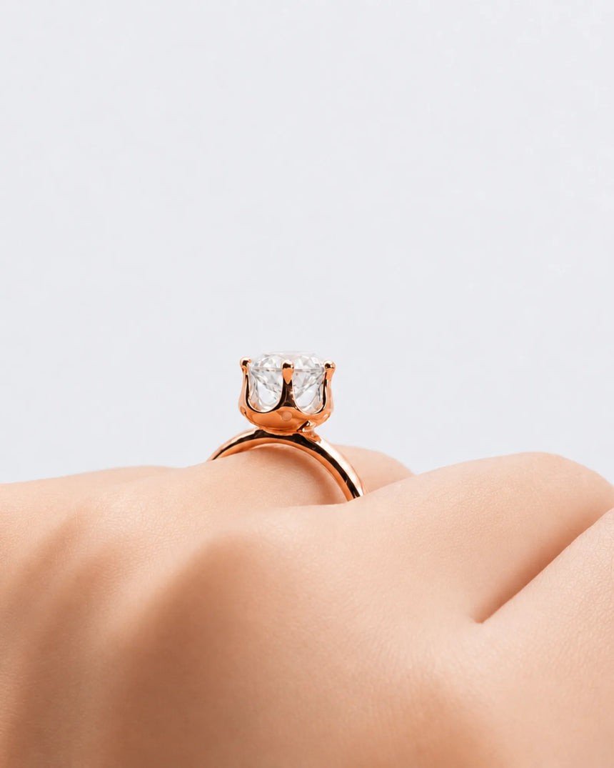Round moissanite solitaire ring in 18K rose gold with tulip-inspired crown and polished band | SARATTI