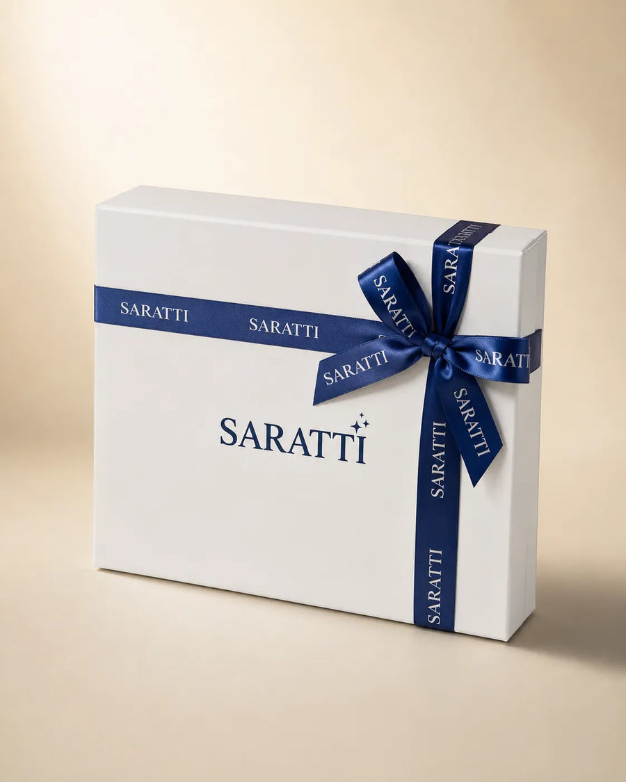 Elegant SARATTI sapphire and diamond three-stone ring shown at a 45-degree angle with polished gold setting and deep blue backdrop